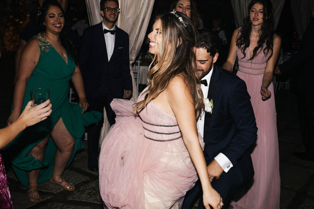 Bride dancing surrounded by guests during wedding party, full of energy and life