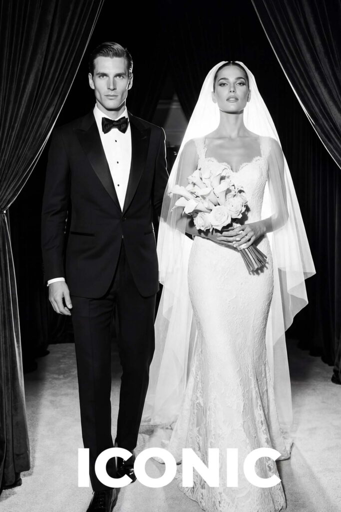 Elegant bride and groom in a black and white editorial wedding portrait, wearing a classic tuxedo and lace gown with veil.