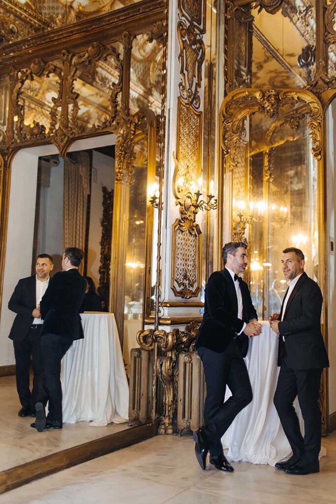 Wedding guests at Castello Brancaccio in Rome inside an elegant mirror hall with golden baroque interiors