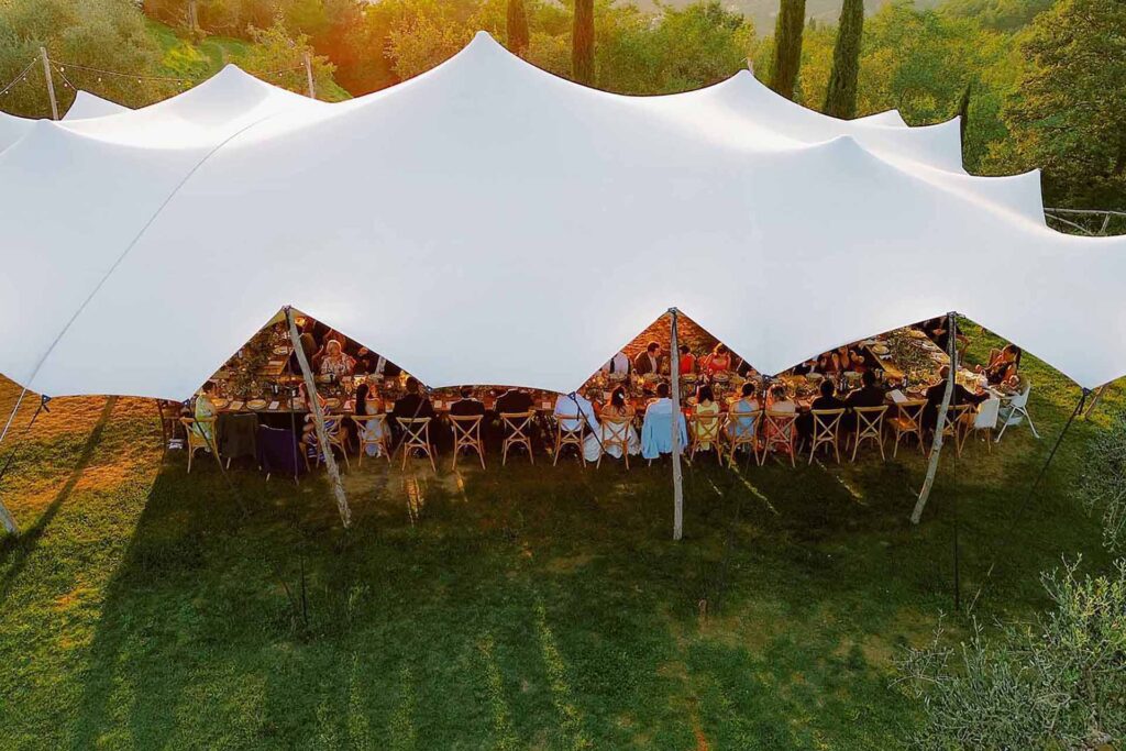 Outdoor wedding reception under a white sail tent at Castello di Ristonchi in Tuscany during golden hour