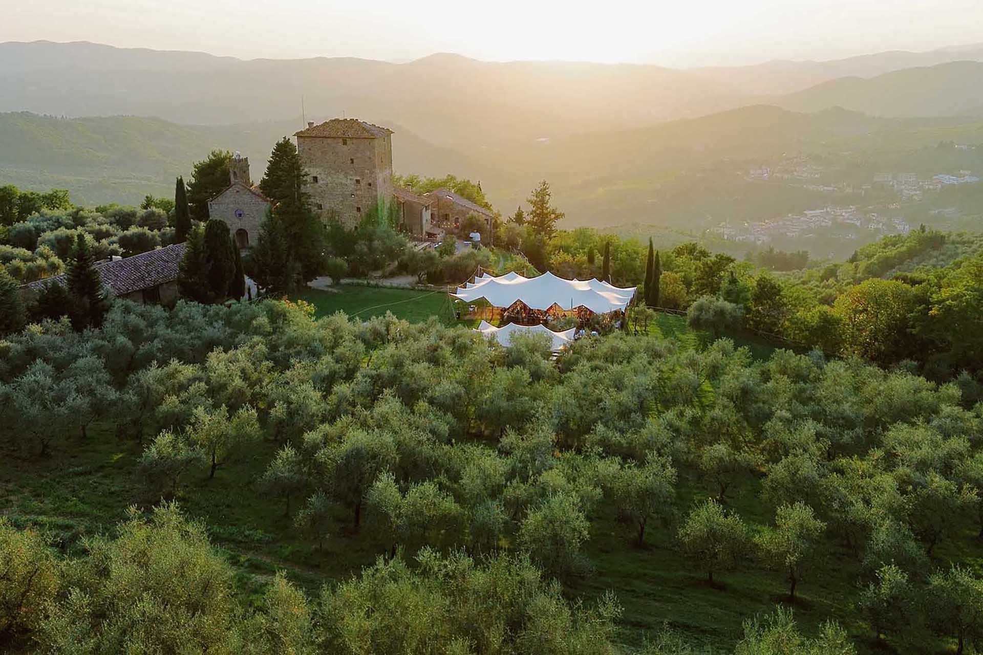 Vista aerea del ricevimento di matrimonio al Castello di Ristonchi a Pelago, Toscana, al tramonto golden hour circondato da uliveti.