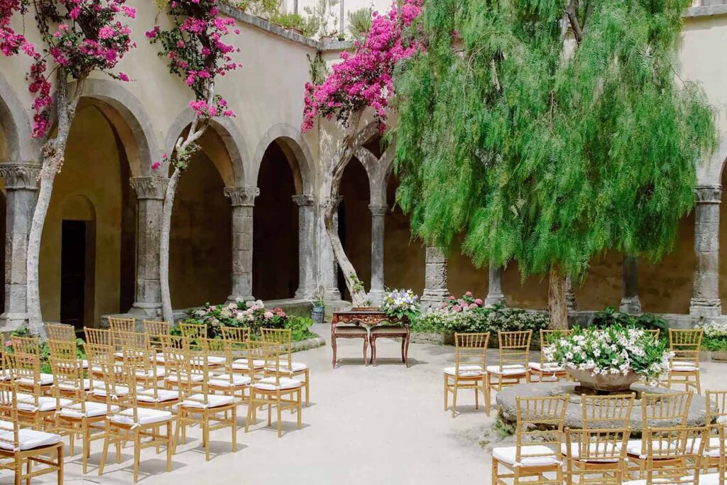 Wedding ceremony setup at Chiostro di San Francesco cloister in Sorrento, Italy with floral decor and golden chairs