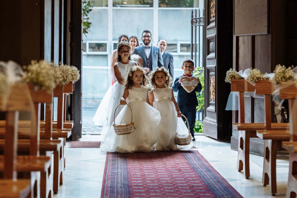 Flower girls walking down the aisle during a church wedding ceremony in Italy