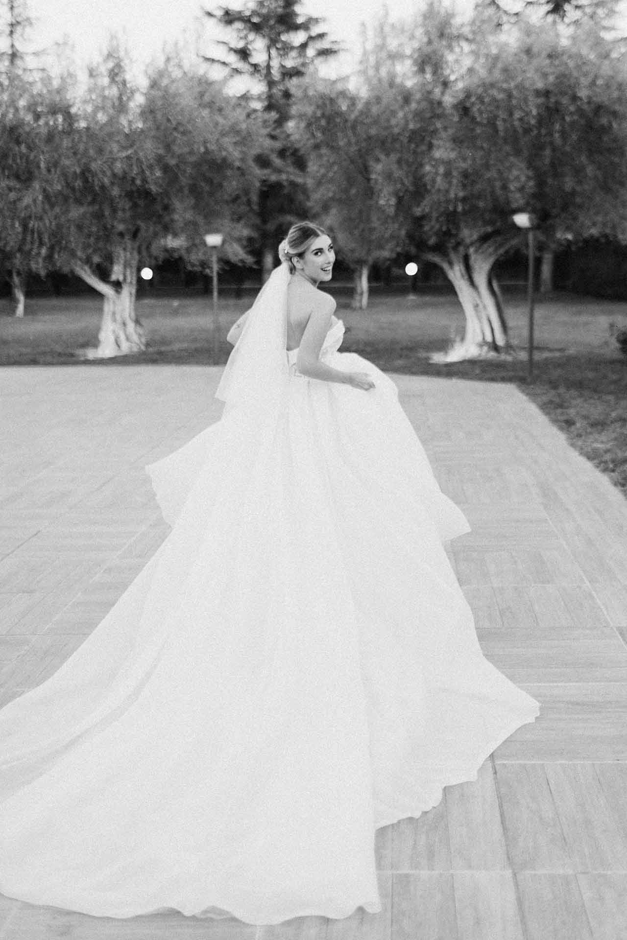 Ritratto in bianco e nero di una sposa con abito fluido che cammina all’aperto in uno stile editoriale fine art.