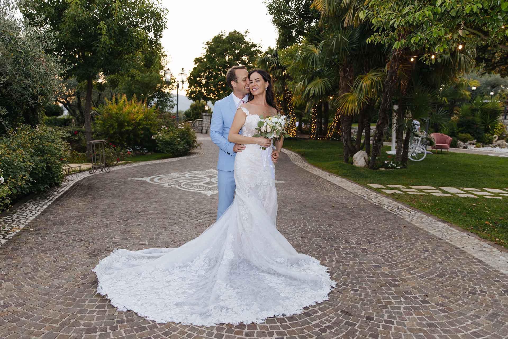 Bride and groom full length wedding portrait at La Grotte Resort in Italy surrounded by garden and elegant evening atmosphere
