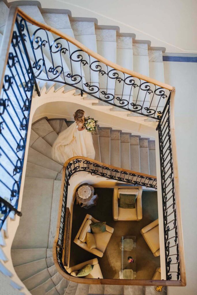 Bride walking down an elegant spiral staircase at Grand Hotel Villa Castagnola in Lugano during a luxury wedding