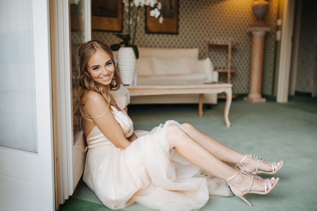 Bride sitting indoors at Hotel Villa Castagnola in Lugano, Switzerland, wearing elegant wedding heels and soft bridal gown