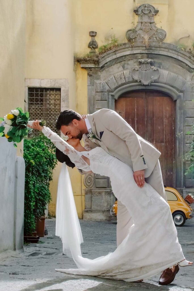 Bride and groom sharing a romantic dip kiss in a historic street in Sorrento, Italy during a luxury destination wedding