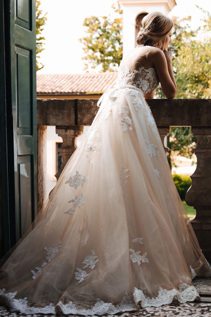 Elegant bride in lace wedding gown standing on an Italian villa balcony during a destination wedding