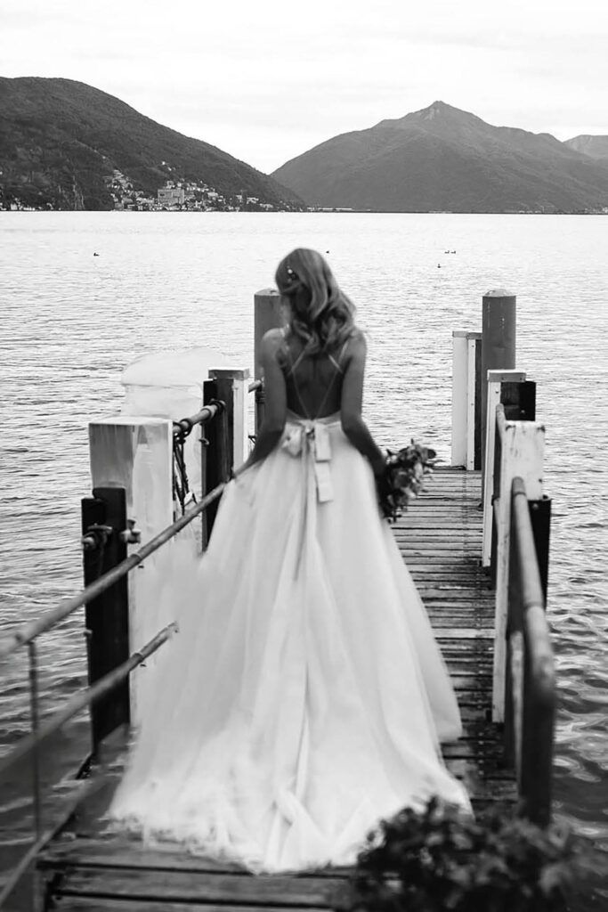 Bride walking on a wooden pier at Grand Hotel Villa Castagnola overlooking Lake Lugano in Switzerland during a luxury wedding