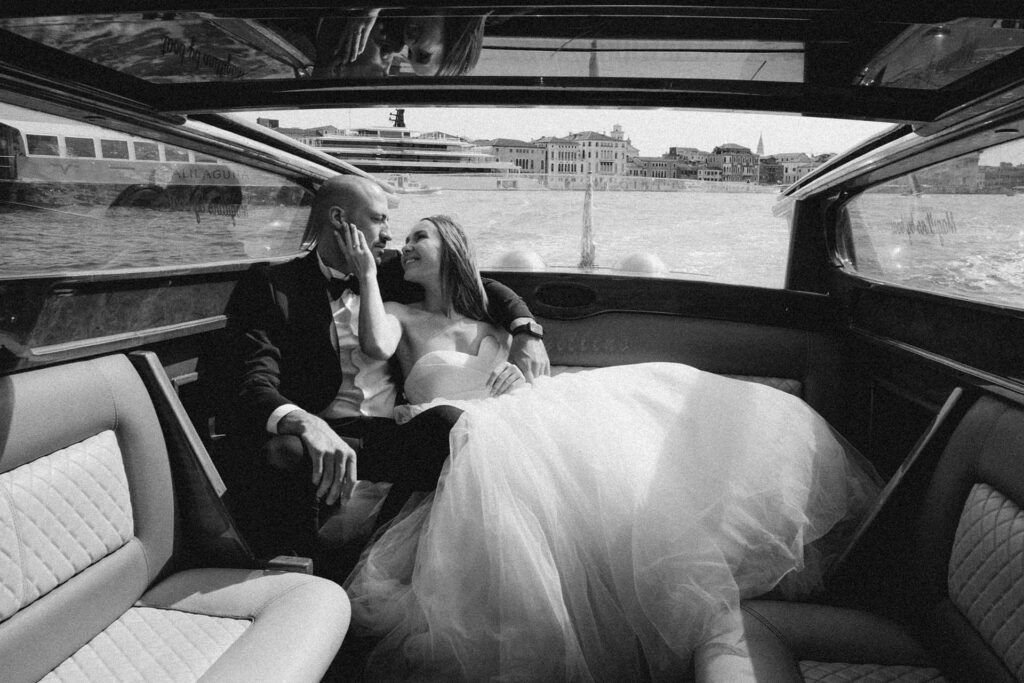Black and white luxury wedding photo in Venice of bride and groom inside a water taxi on the Grand Canal