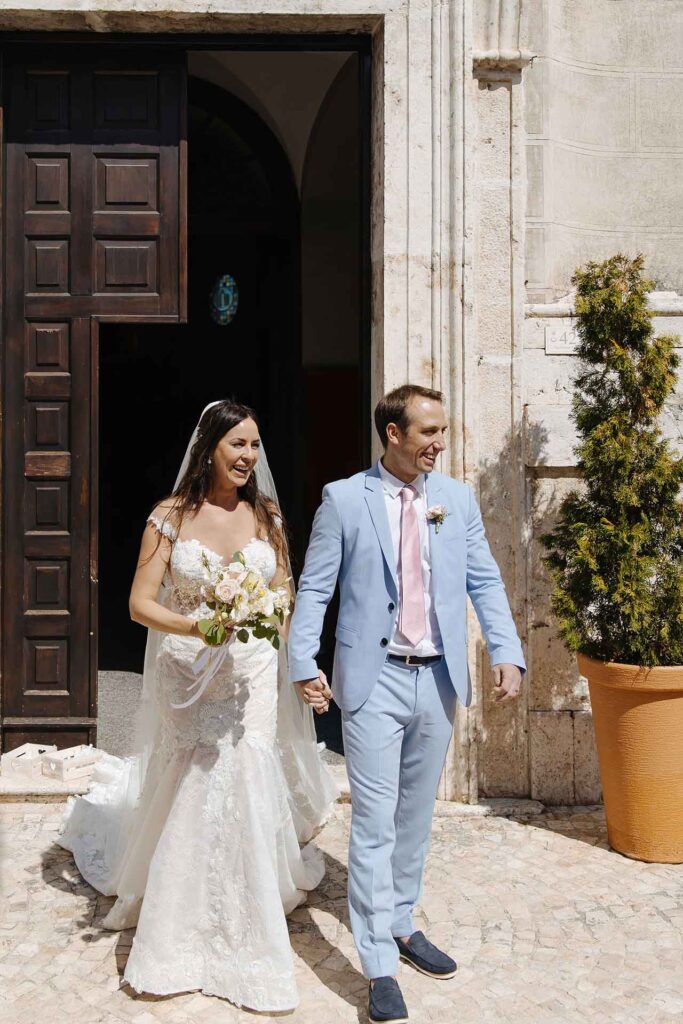 Couple exiting church as newlyweds with guests celebrating in Picinisco, Italy
