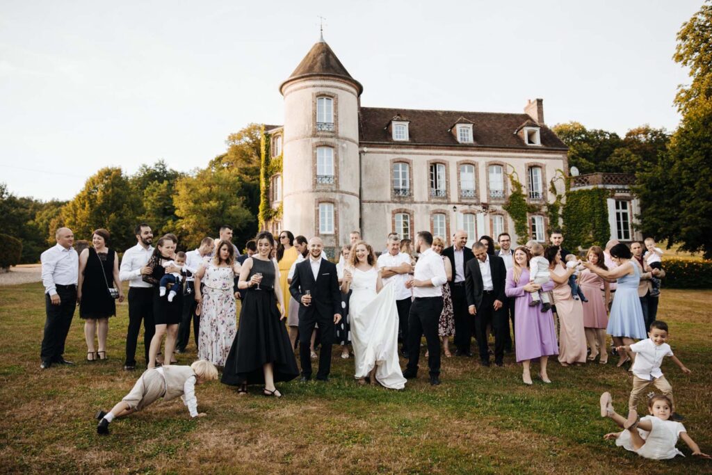 Bride and groom celebrating with guests in front of a French château near Paris during a luxury destination wedding in France