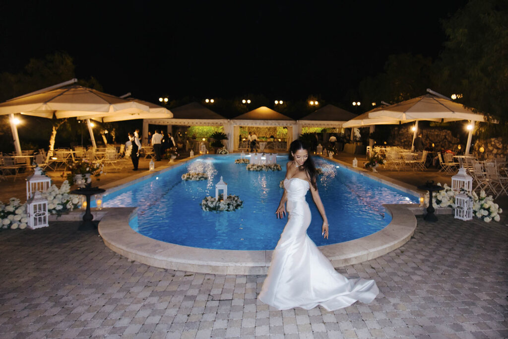 Bride posing by illuminated pool during a luxury wedding reception in Rome, Italy at night
