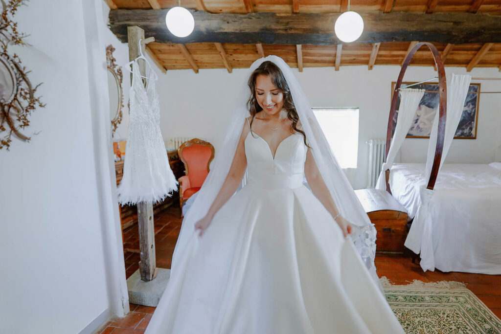 Bride getting ready at Castello di Ristonchi in Tuscany wearing elegant wedding dress inside rustic Italian villa bedroom