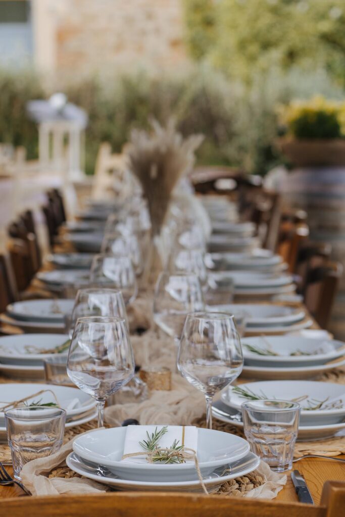 Rustic luxury wedding reception table setup in Tuscany, Italy with elegant plates, glassware and countryside decor
