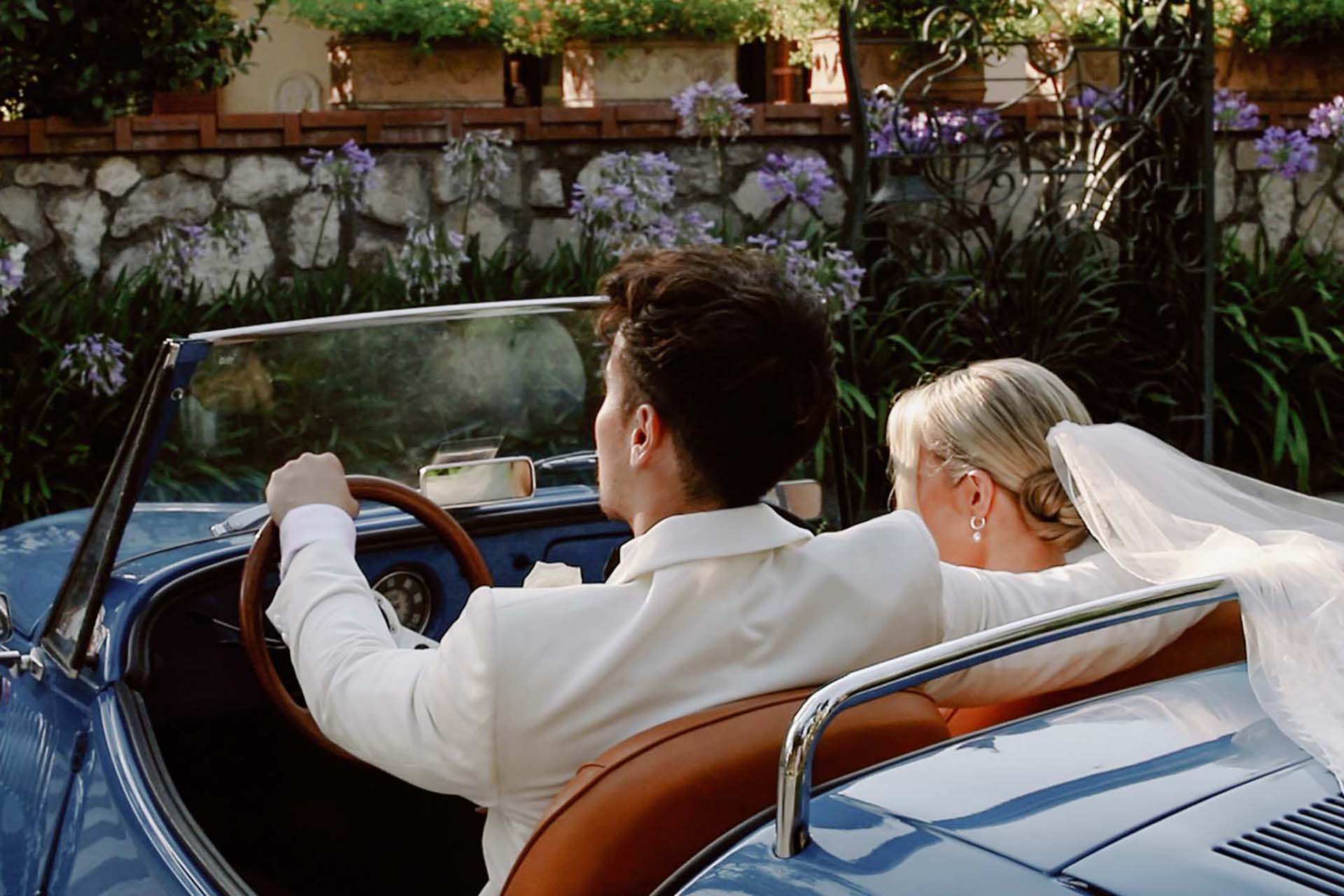 Gli sposi in una decappottabile blu vintage a Villa Antiche Mura a Sorrento, sulla Costiera Amalfitana.