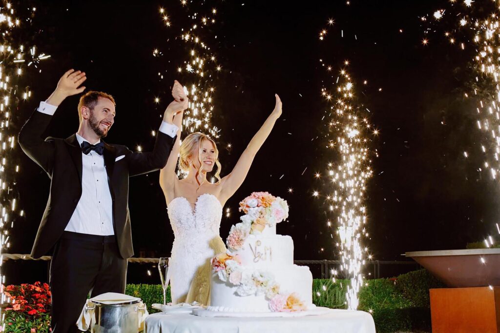 Bride and groom celebrating wedding cake cutting with fireworks at Villa e Palazzo Aminta on Lake Maggiore, Italy