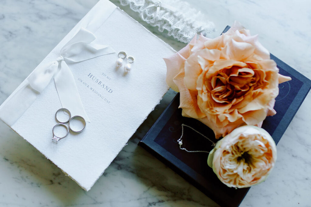 Luxury wedding details at Villa e Palazzo Aminta on Lake Maggiore featuring rings, invitation, and floral arrangement