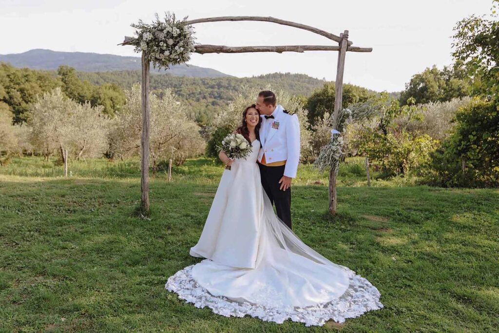 Rustic outdoor wedding ceremony arch with rolling Tuscan hills in background