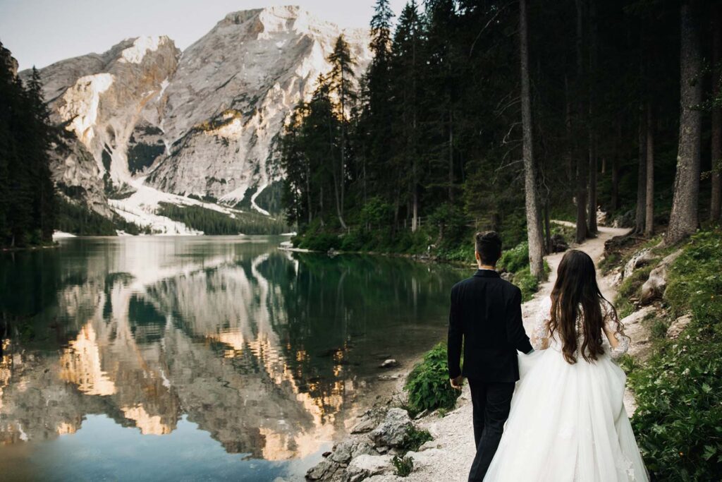 Bride and groom walking beside Lake Braies in the Italian Dolomites during an intimate destination wedding