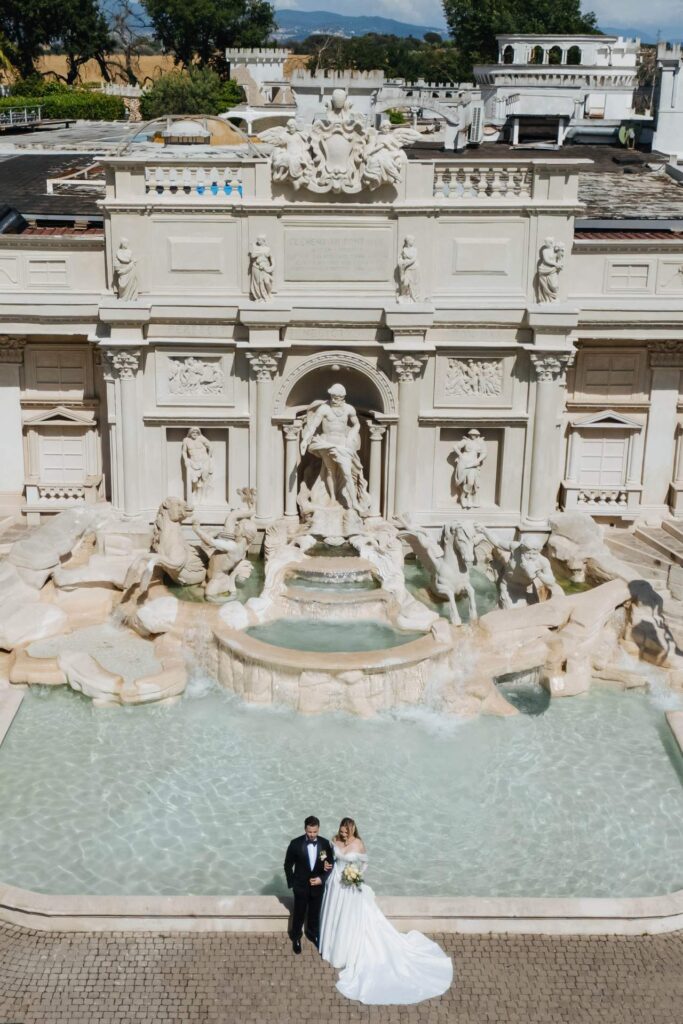 Aerial view of the bride and groom beside the monumental fountain at Villa Il Lago dei Cigni