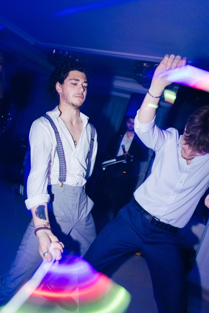Wedding guests dancing with colorful light sticks during late-night celebration in Rome