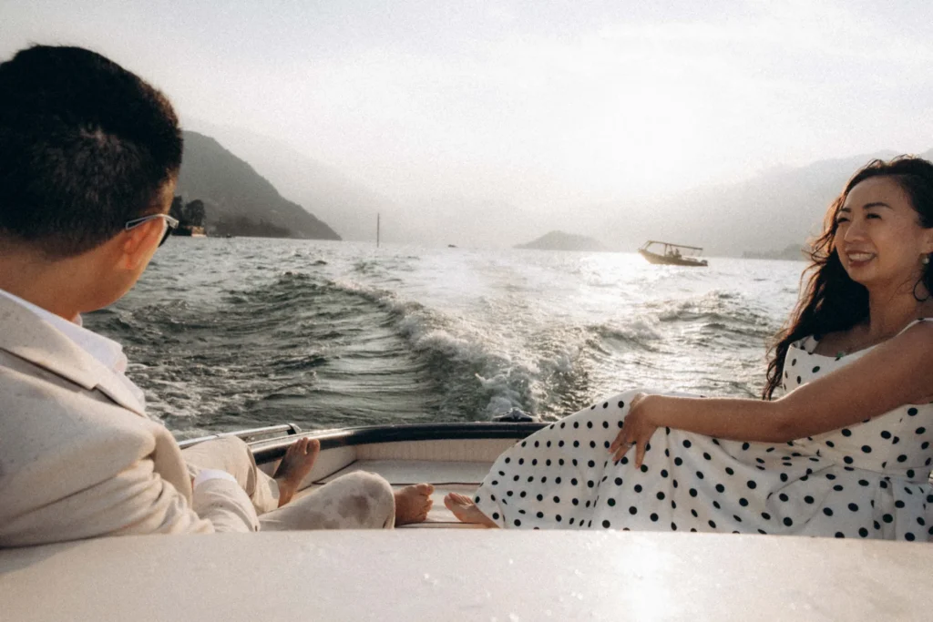 Couple relaxing opposite each other in a motorboat as evening light falls on Lake Como